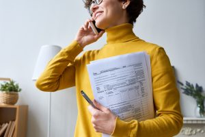 Young woman talking on the phone and holding multiple IRS forms