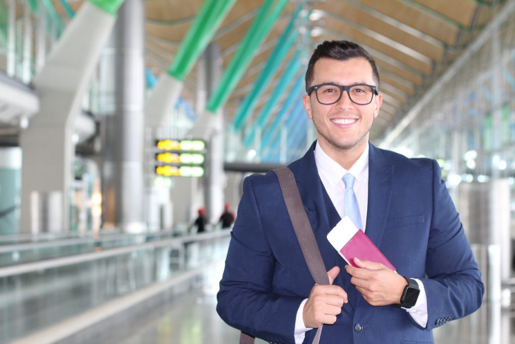 Young Businessman In Airport With Passport To Work Overseas; Foreign Work Concept