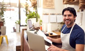 small business owner wearing an apron works on a laptop to determine if business grants are taxable income