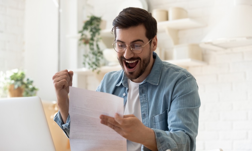 man looks excitedly at his tax return because he lowered his taxes by understanding a tax credit vs. deduction