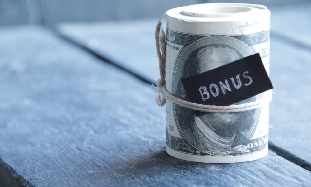 A roll of cash with a “bonus” label signifies a bonus waiting to be taxed.