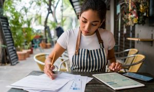 A business owner at a table working on her small business accounting