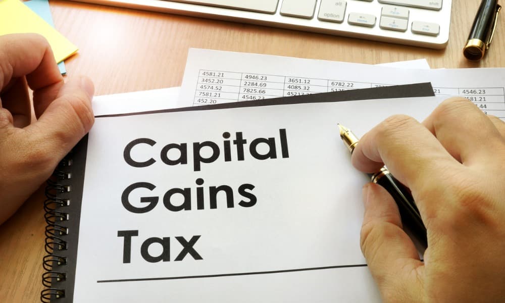 Capital gains tax documents on a desk near a person’s hands