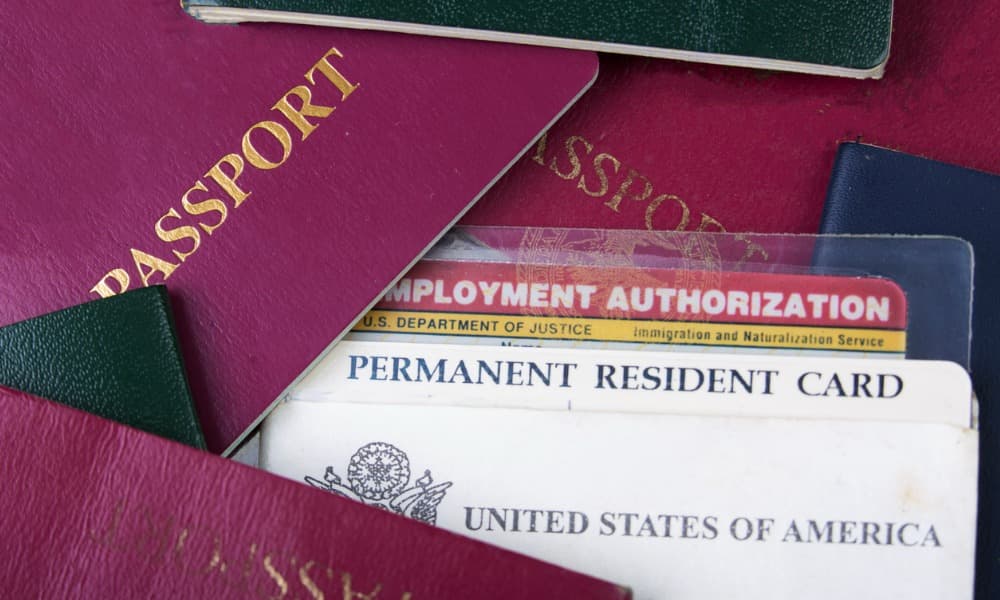 A Stack Of Passports And A U.s. Permanent Resident Card, Representing Foreign Asset Reporting