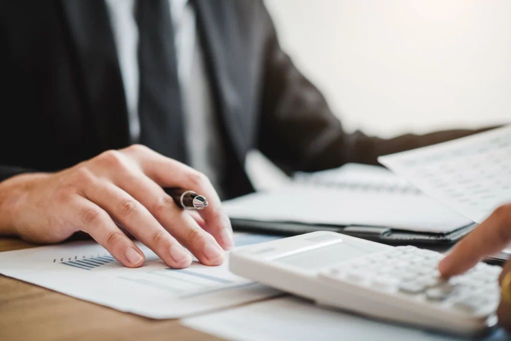 An attorney working at his desk with a calculator and paperwork. 