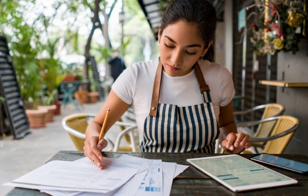A Business Owner At A Table Working On Her Small Business Accounting